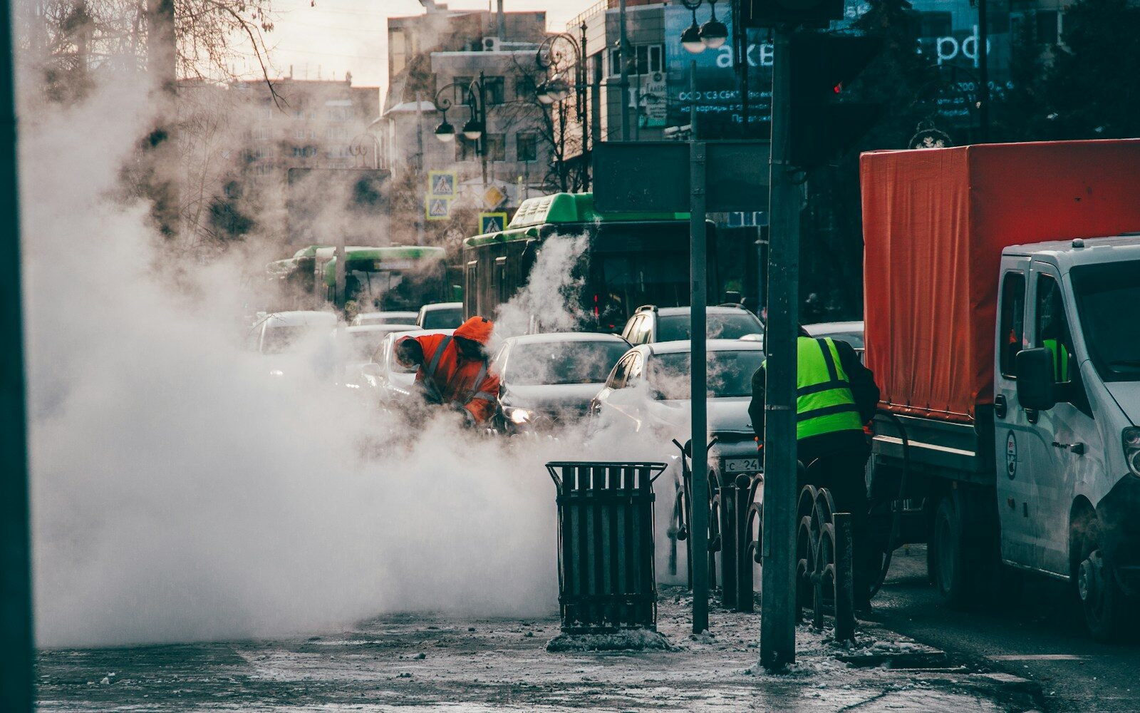 a man in an orange safety vest standing in the middle of a street