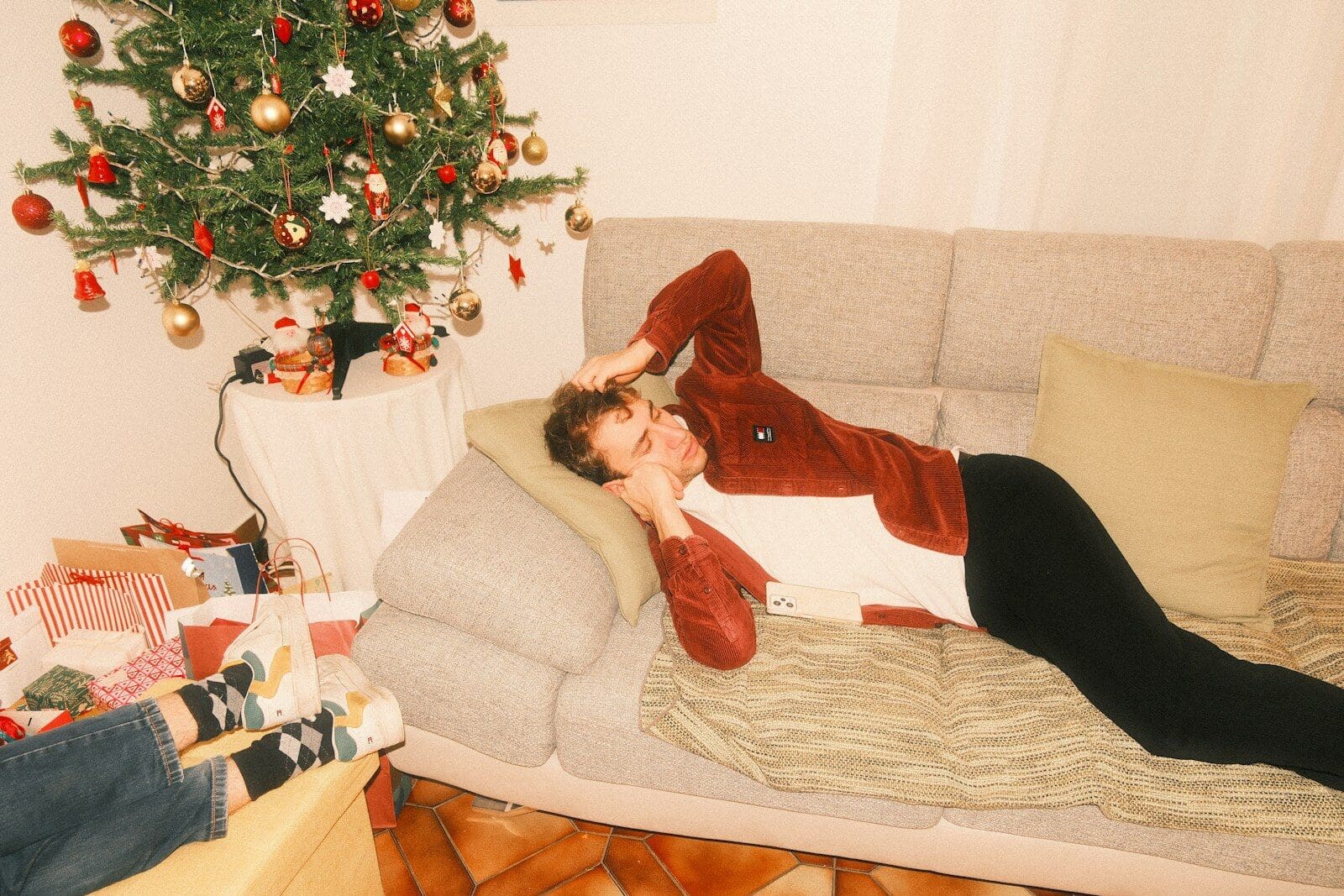 A person relaxes on a couch near a christmas tree